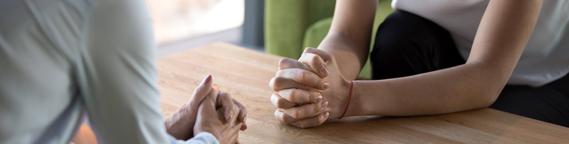 Two people discuss face to face with their hands clasped